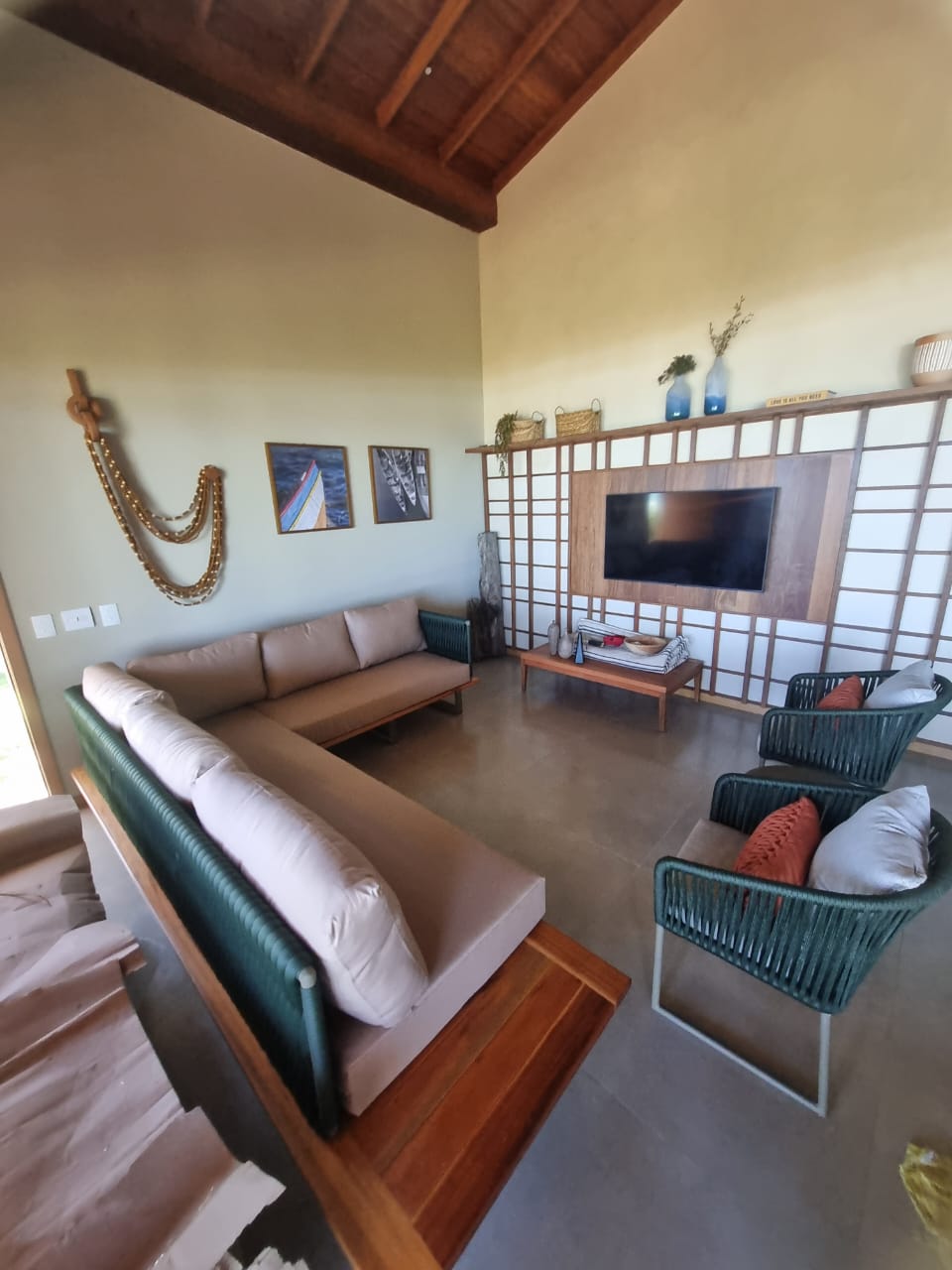 Sala de estar com pé-direito duplo, painéis shoji e mobiliário em cordas e madeira